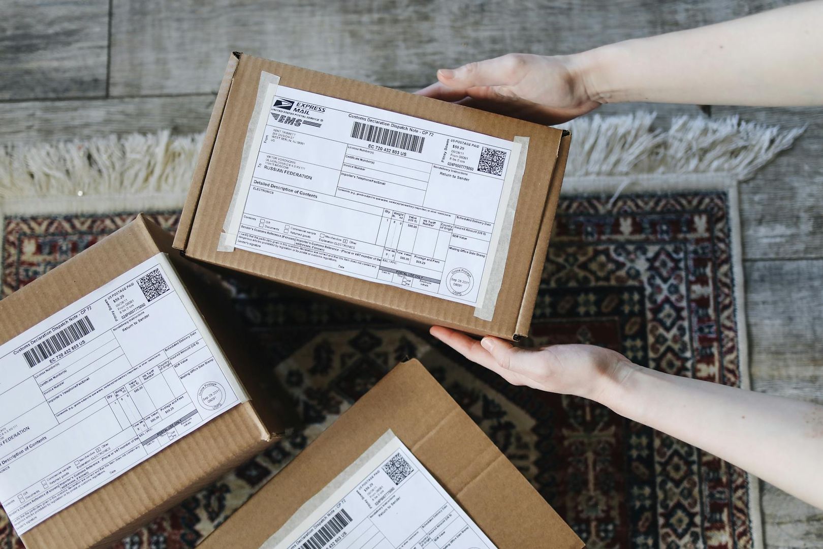 Händer som håller i ett paket med en tydlig fraktsedel för internationell frakt.