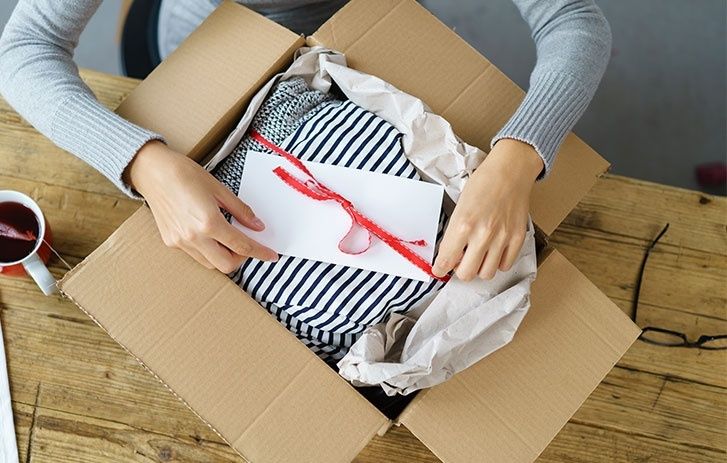 Person öppnar ett paket med randiga kläder och ett kort
