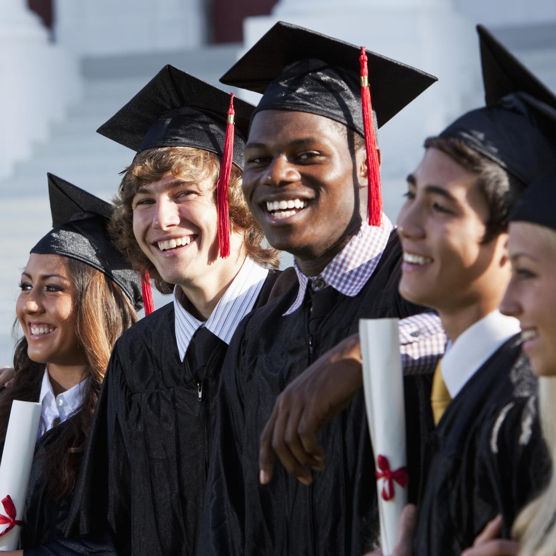 En grupp studenter i traditionella studentmössor och examenskläder som ler glatt tillsammans.